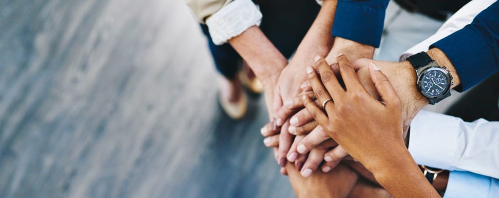 Photo of hands coming together to represent team huddle and collaboration.