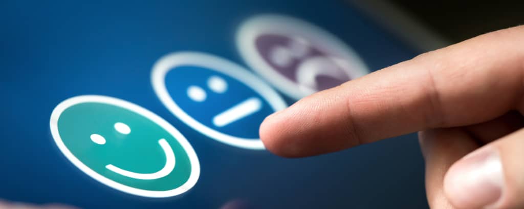 Photo of finger preparing to give feedback by choosing a happy, neutral, or sad face icon