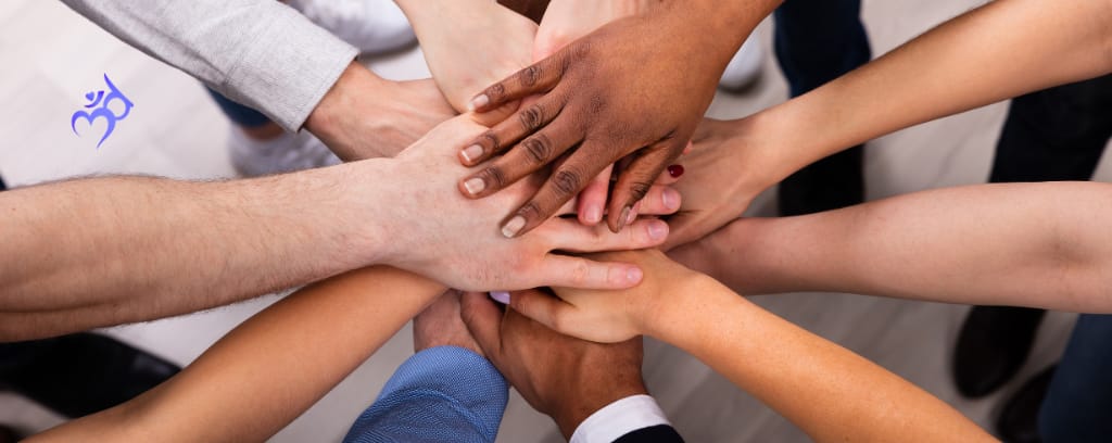 Photo of hands of many different skin tones stacked atop one another in unity