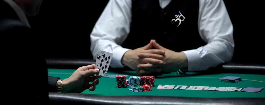 Photo of gambler at table with many chips in front of the dealer
