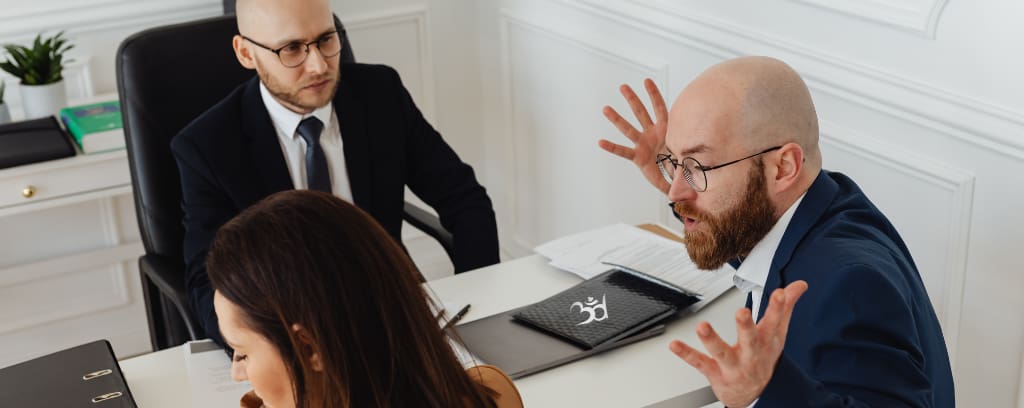 Photo of co-worker throwing hands in air and verbally attacking another while a third looks confused