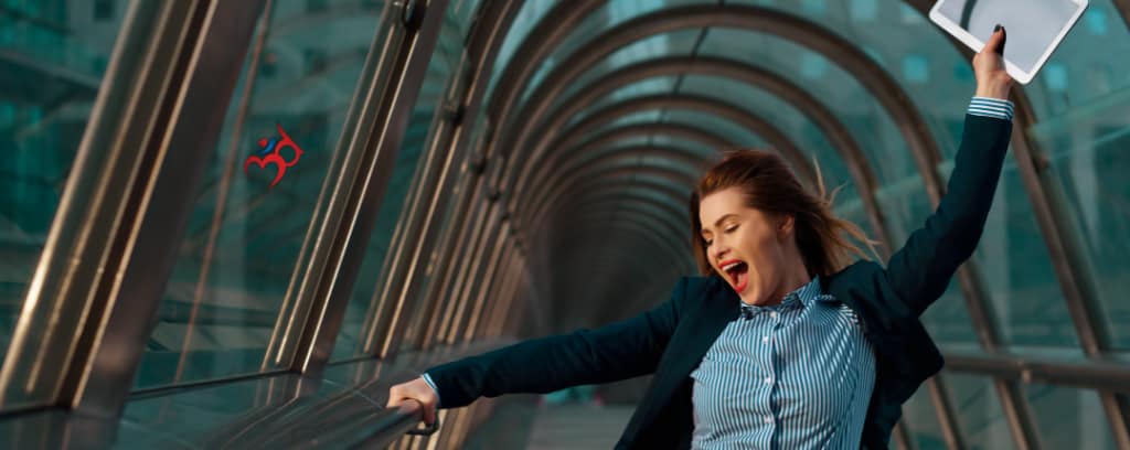 Photo of joyously smiling employee with one hand in the air holding a smart pad while leaving work permanently