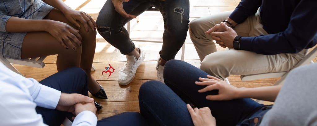Photo of employees seated in a circle and sharing safely