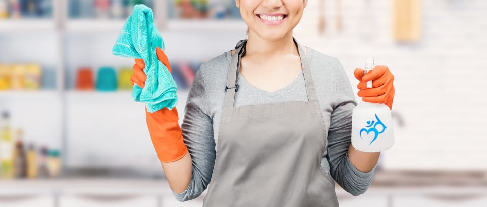 Photo of cleaning person holding trash bags in one hand and spray bottle in the other