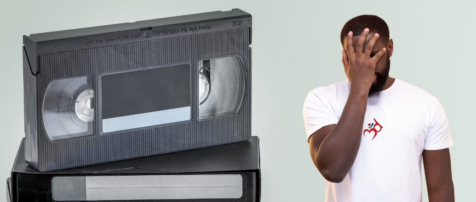 Photo of old VHS tapes next to employee in Third Ear Conflict Resolution T-shirt expressing dismay about ineffective workplace training videos