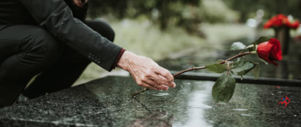 Photo of funeral director placing a red rose on a casket