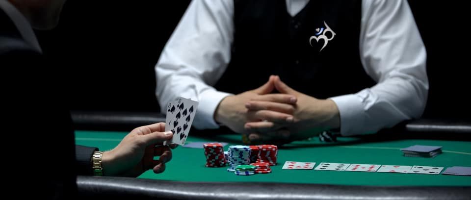 Photo of gambler at table with many chips in front of the dealer