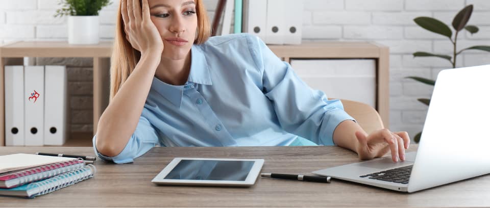 Photo of worker with head propped up on desk with one hand and boredom expression