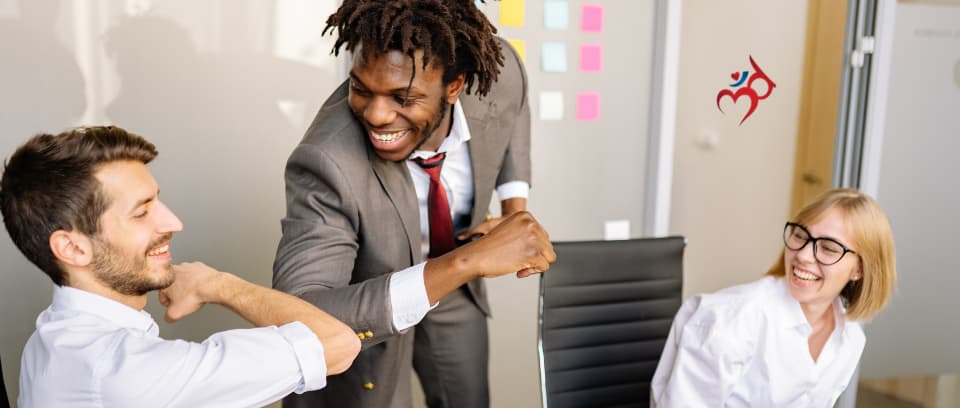 Photo of smiling boss bumping elbows with smiling employee while co-worker smiles