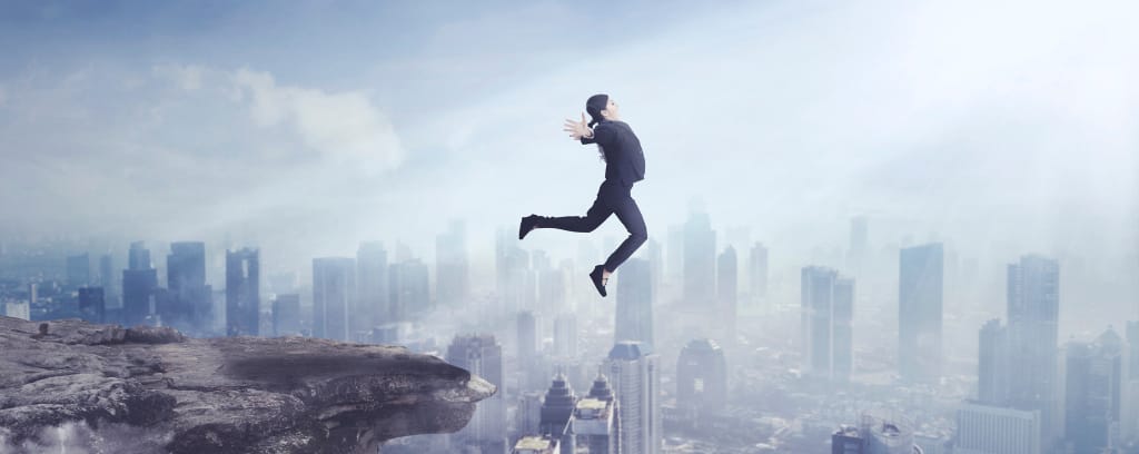 Photo of person leaping from a ledge into a large city