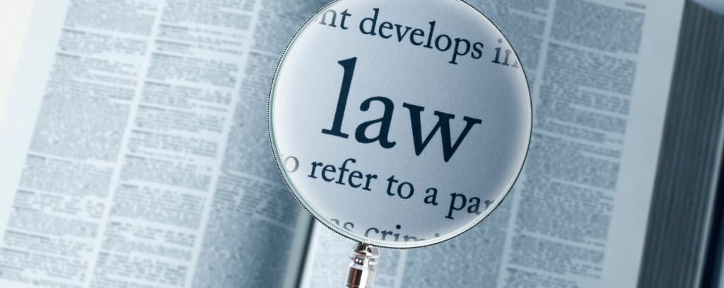 Photo of magnifying glass increasing the word  "law" in a book