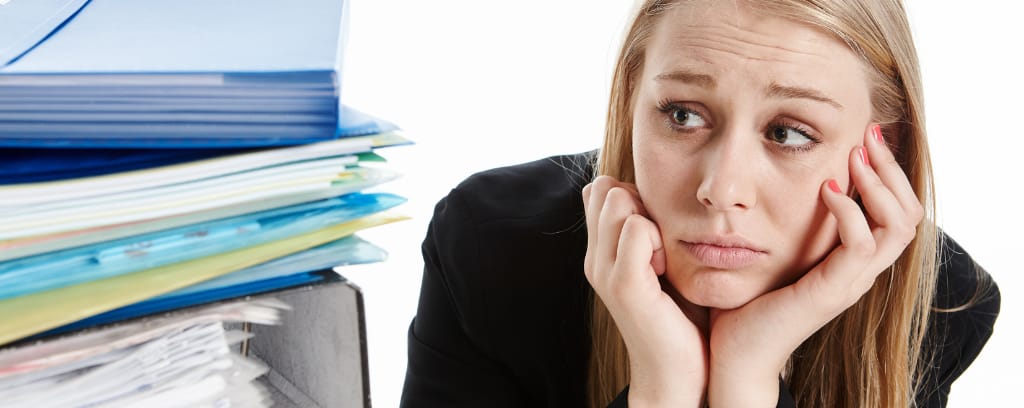 Photo of intern next to piles of work for which no pay is offered.