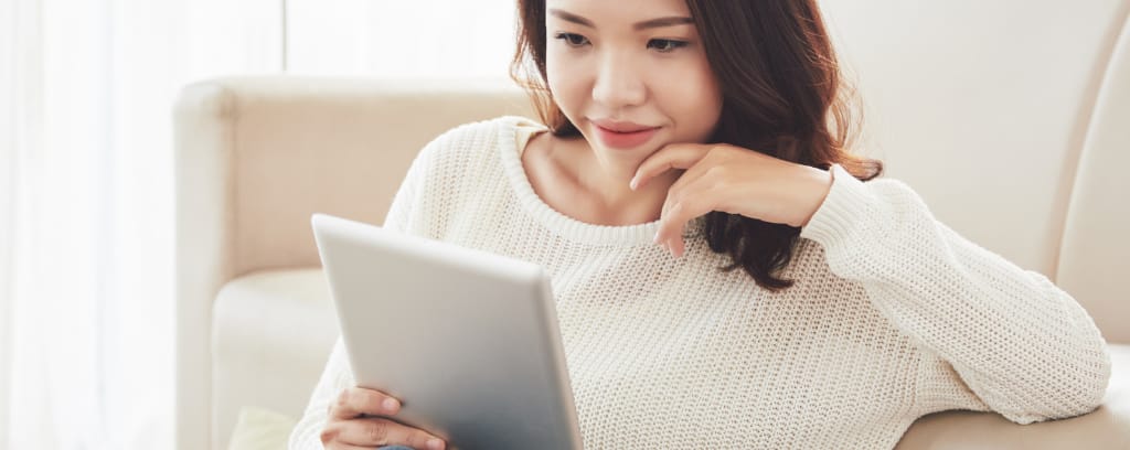 Photo of employee in white sweater reading from an iPad or tablet.