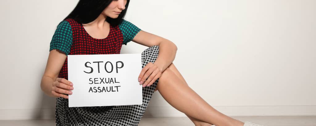 Photo of person holding sign that reads "STOP sexual assault"