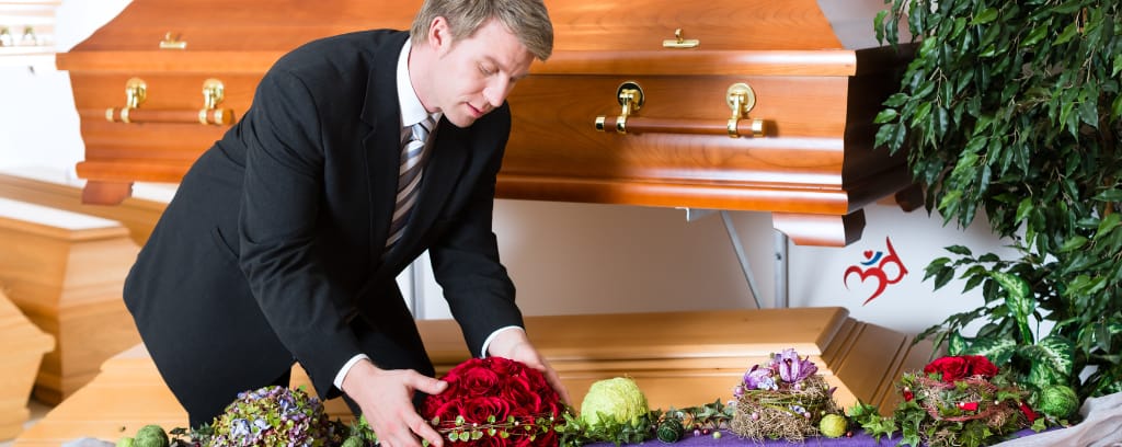 Photo of funeral director preparing casket and flowers for service 