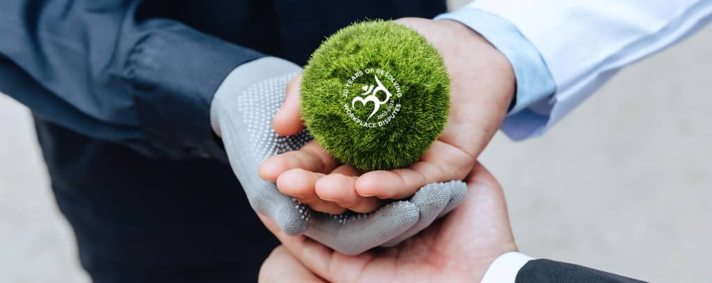 Photo of four human hands stacked to support a round plant