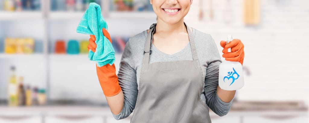 Photo of cleaning person holding trash bags in one hand and spray bottle in the other