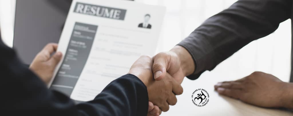 Photo of two people shaking hands while one holds a resume