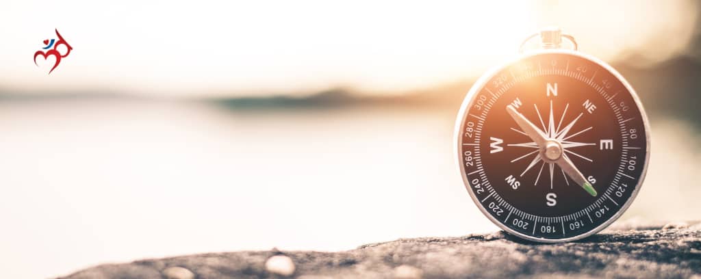 Photo of compass on a beach at sunrise