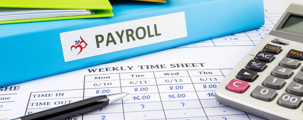 Photo of binder labeled "payroll" on desk with time sheet