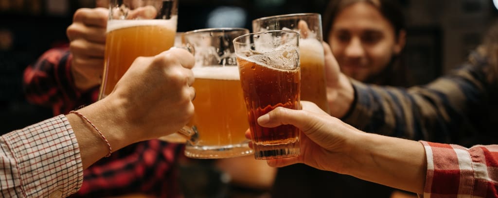 Photo of people toasting by clinking their beer glasses together