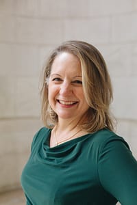 Nance Schick smiling and wearing green dress outside New York Public Library in Midtown Manhattan