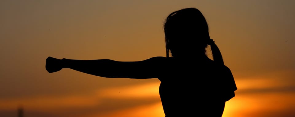 Photo of person silhouette punching powerfully with sundown in the background