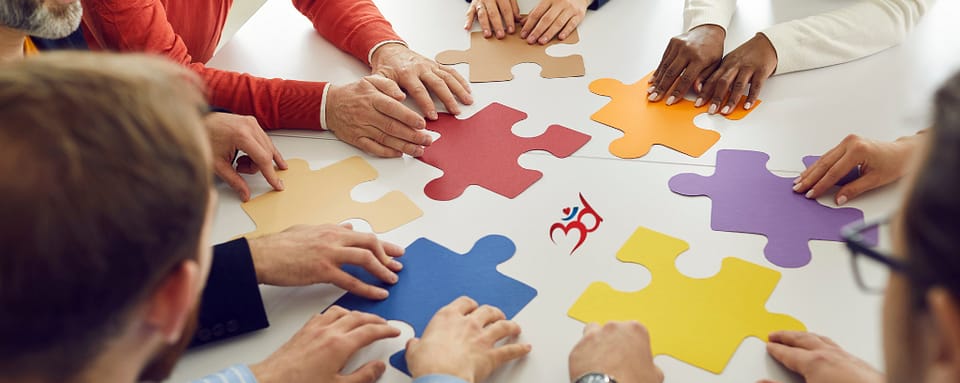 Photo of workers at a table putting large puzzle pieces of different colors together